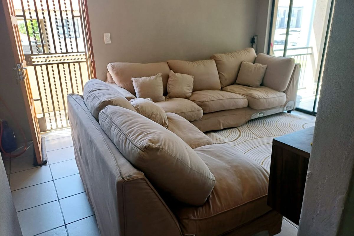 A living room area featuring tiled flooring, a security gate at the entrance, and sliding glass doors leading to an outdoor space.