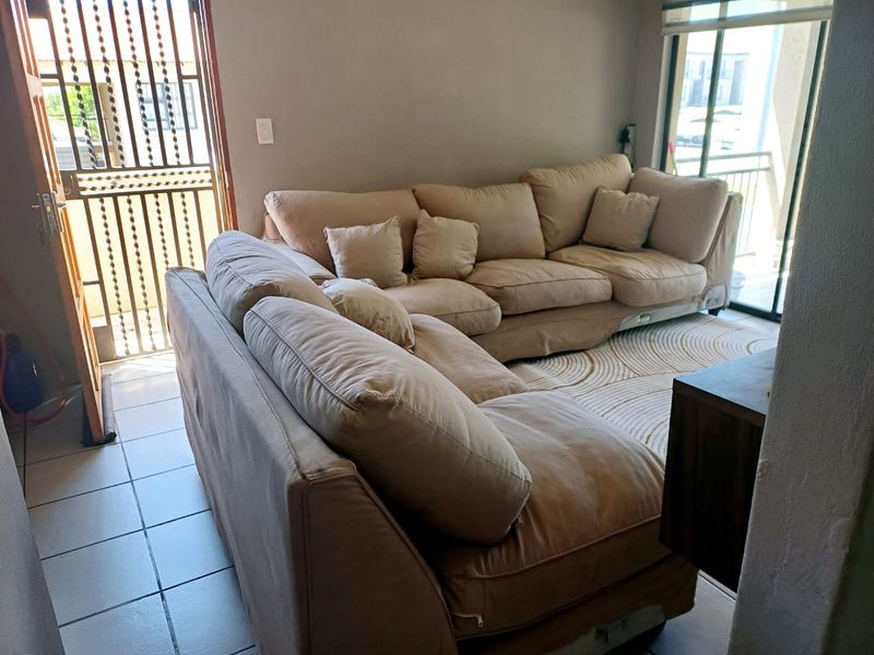 A living room area featuring tiled flooring, a sliding glass door leading to a balcony, and a security gate at the entrance.