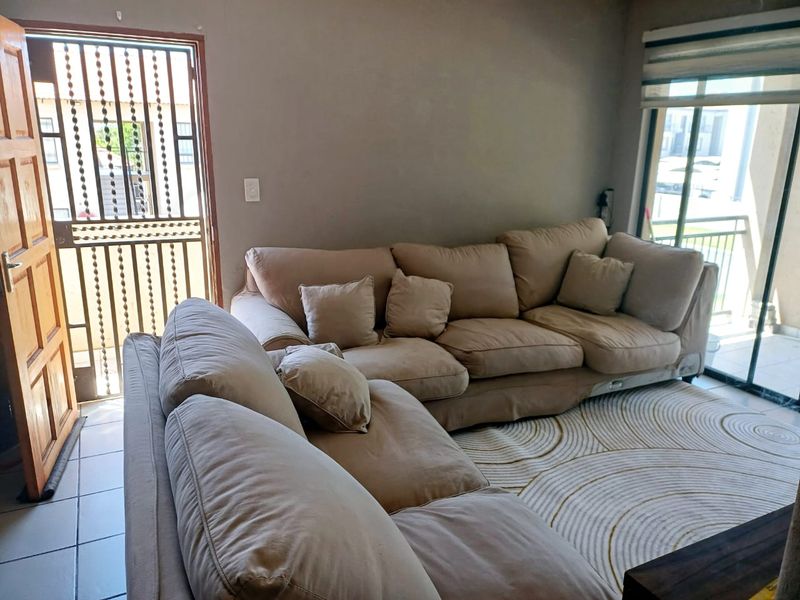 Living room featuring tiled flooring, a sliding glass door with roller blinds, and a security gate leading to the exterior.