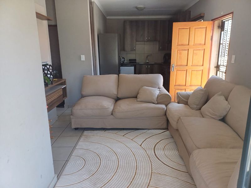 Open-plan living area featuring tiled floors and an integrated kitchen with built-in cabinetry, providing a functional and connected living space.