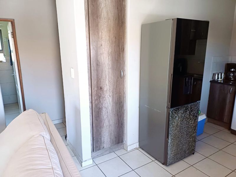 Open plan living area featuring tiled flooring and a built-in storage cupboard, providing a functional layout for the apartment.