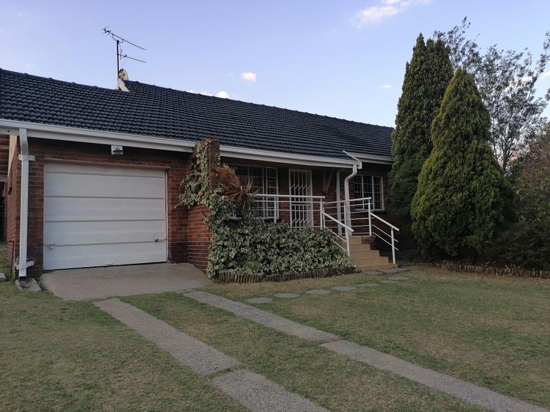 Front elevation of a single-story brick house featuring a single garage, tiled roof, and a small elevated entrance porch with security gate.