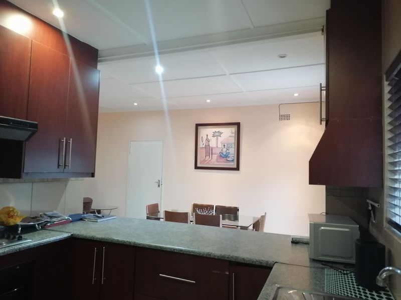 Open-plan kitchen and dining area featuring dark wood cabinetry, granite countertops, and recessed lighting, creating a functional and connected living space.