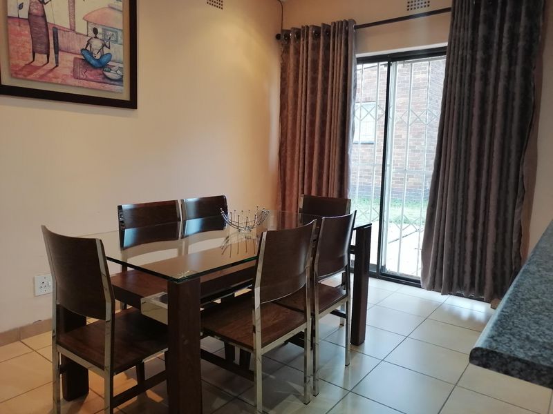 Dining area featuring ceramic floor tiles and a sliding glass door with security gate providing access to the exterior.