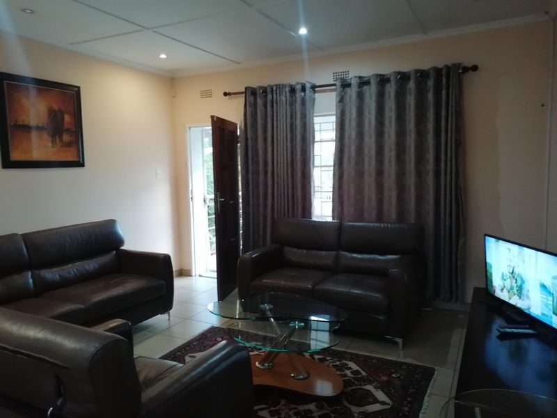 A comfortable living room featuring tiled flooring, recessed downlighting, and direct access to an outdoor area through a security gate.