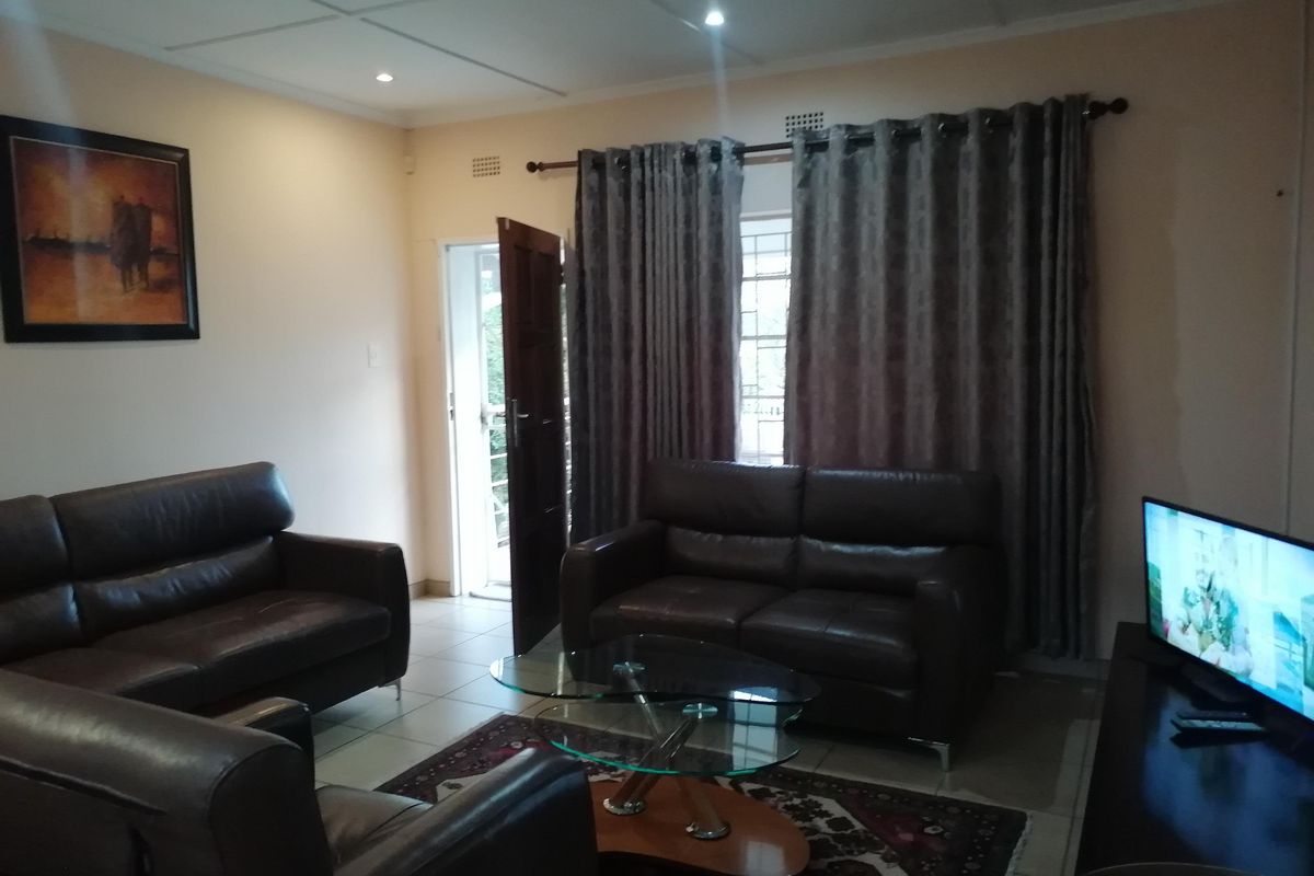 A comfortable living room featuring tiled flooring, recessed downlighting, and direct access to an outdoor area through a security gate.