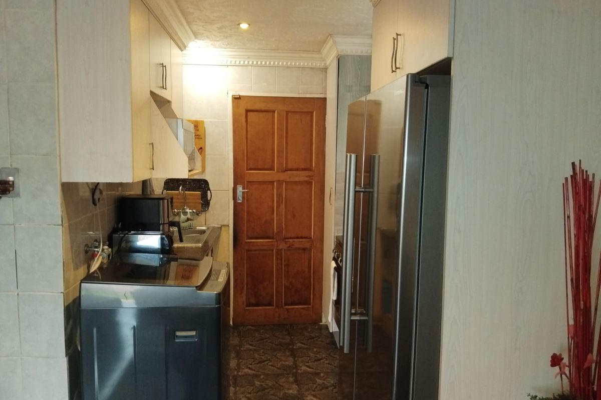 A functional kitchen area featuring built-in cabinetry, tiled backsplash, and a classic timber door, providing a practical layout for daily use.