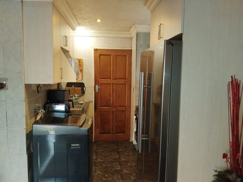 A functional kitchen area featuring built-in cabinetry, tiled backsplash, and a classic timber door, providing a practical layout for daily use.