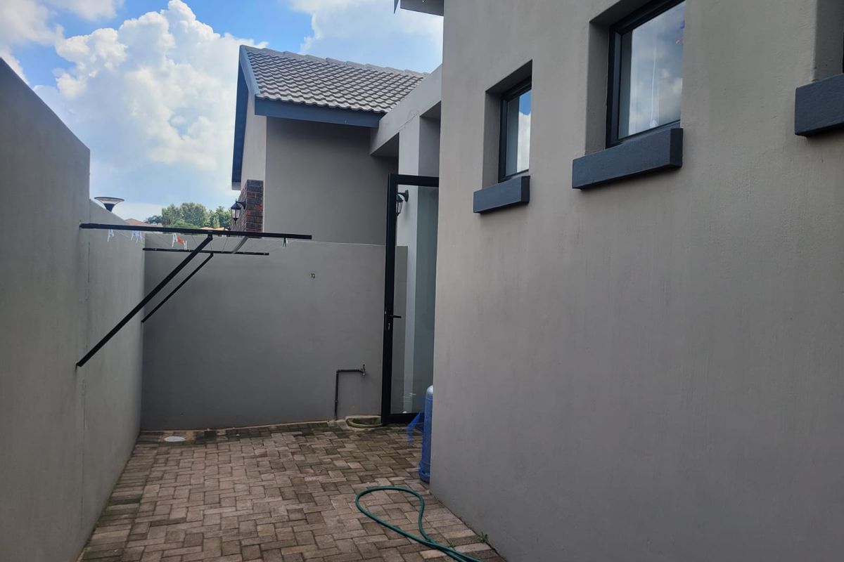 A neat and private rear courtyard featuring paved flooring, a wall-mounted drying rack, and an external water tap.