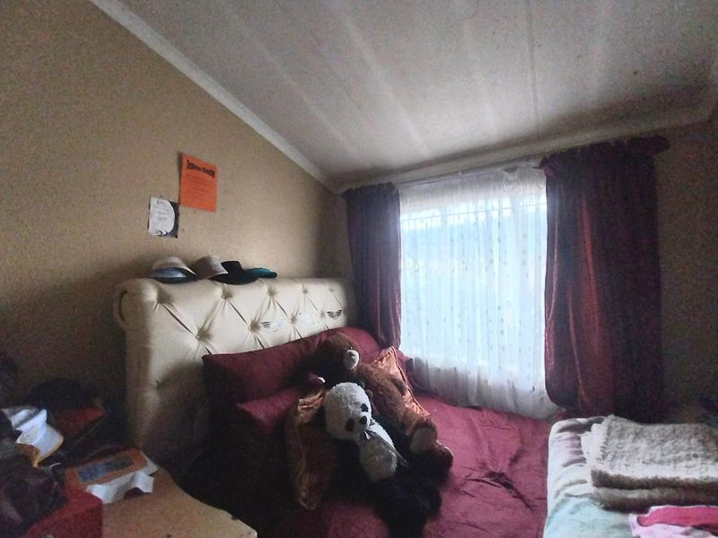 A bedroom featuring a tufted headboard, large window with curtains, and neutral wall tones.