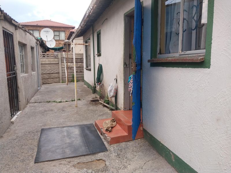 A view of the rear exterior area featuring concrete paving, a small entrance step, and access to the side of the house.