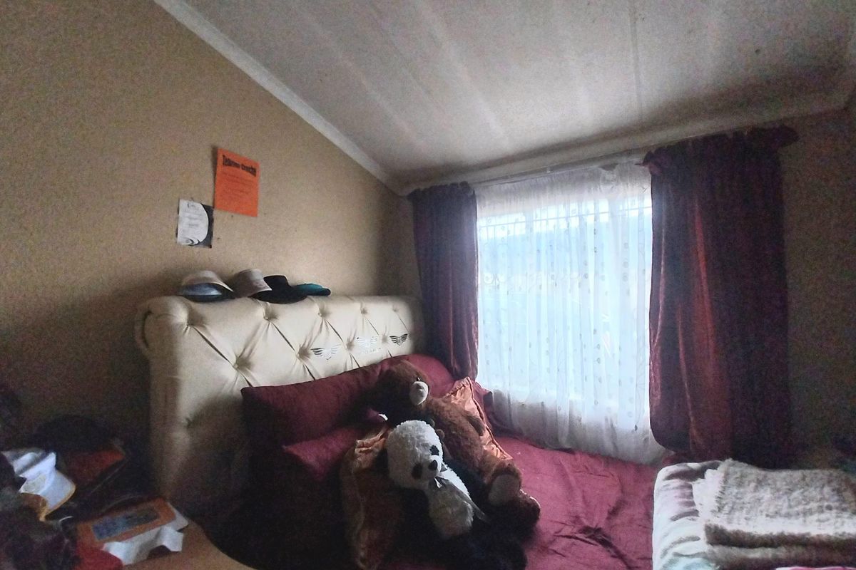 A bedroom featuring a tufted headboard, large window with curtains, and neutral wall tones.