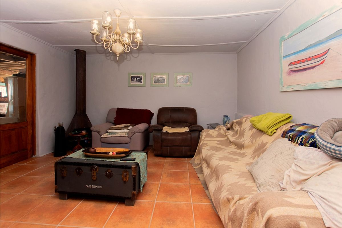A living room featuring terracotta tiled flooring and a freestanding fireplace, with potential for cosmetic updates to the walls and ceiling.