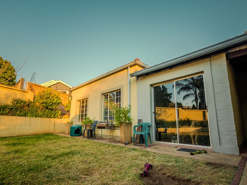 Rear exterior view of the duet property featuring a concrete patio, lawn area, and sliding glass doors leading into the home.
