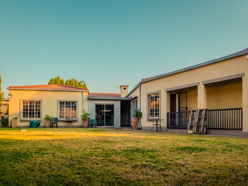Rear view of the duet property featuring a covered patio, sliding glass doors, and a spacious private garden area.