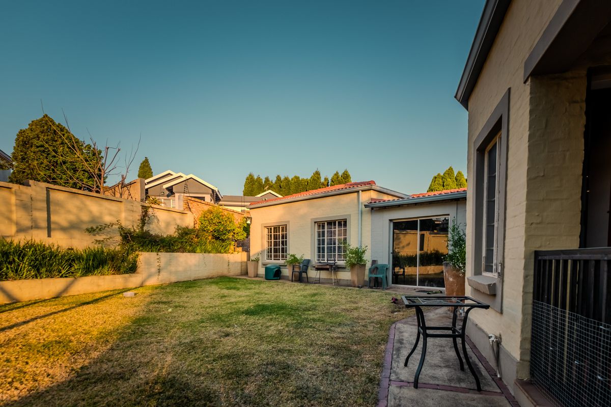 A private rear garden featuring a lawn area, perimeter wall, and sliding glass door access to the main dwelling.