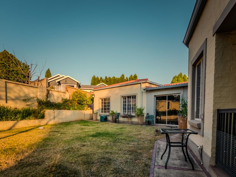 A private rear garden featuring a lawn area, perimeter wall, and sliding glass door access to the main dwelling.