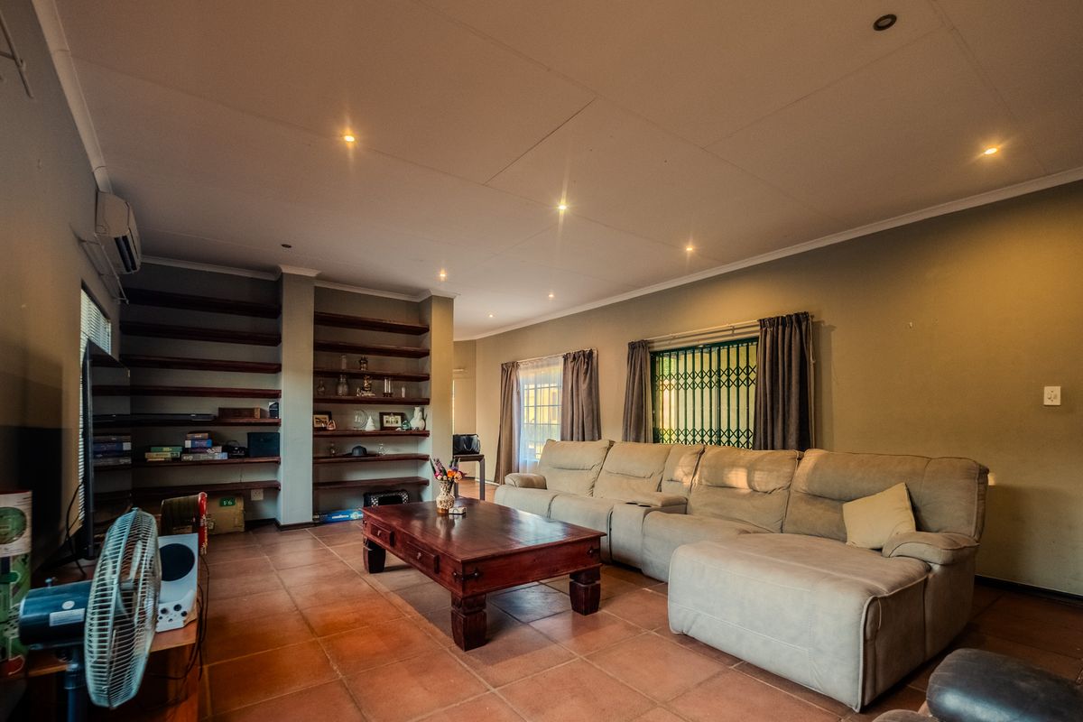 Spacious living room featuring tiled flooring, recessed lighting, built-in shelving units, and an air conditioning unit.