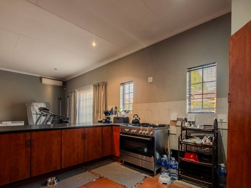 A functional kitchen featuring wooden cabinetry, a gas stove with oven, tiled backsplash, and an integrated air conditioning unit.