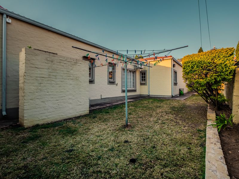 Rear exterior view of the property featuring a private garden area, brick boundary walls, and a rotary washing line.