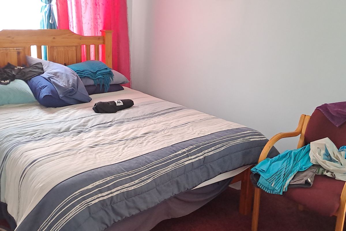 A standard bedroom featuring carpeted flooring and window treatments.