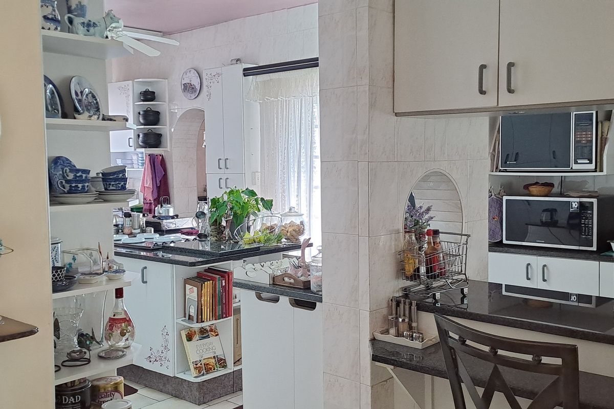 A functional kitchen featuring granite countertops, built-in cabinetry, and a breakfast bar, offering a practical layout with integrated appliance spaces.