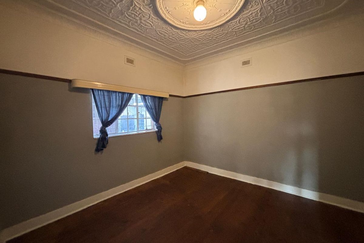 A vacant bedroom featuring original decorative pressed metal ceiling, timber picture rails, and polished hardwood flooring.