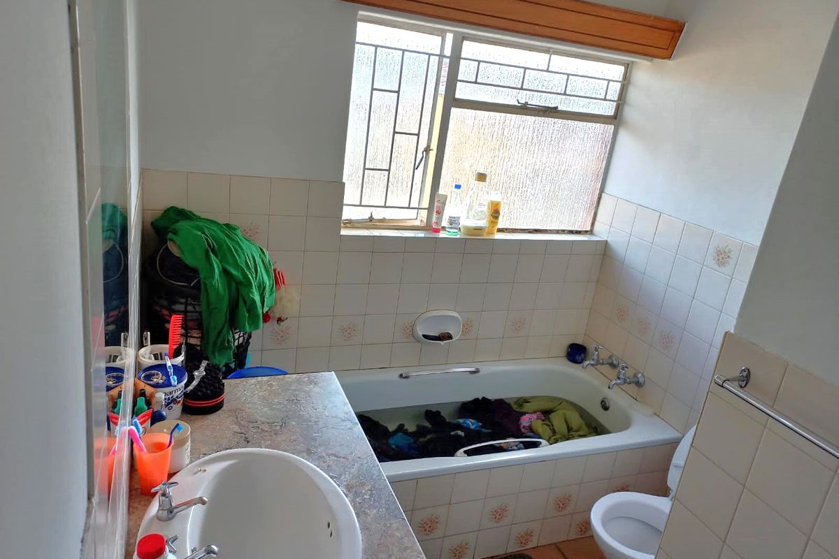 A functional bathroom featuring a built-in bathtub, vanity basin with laminate countertop, and tiled wall finishes.