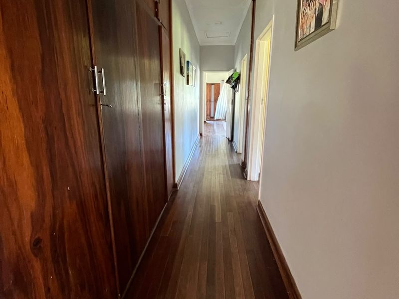 A long hallway featuring polished timber flooring and extensive built-in wooden cabinetry for storage.