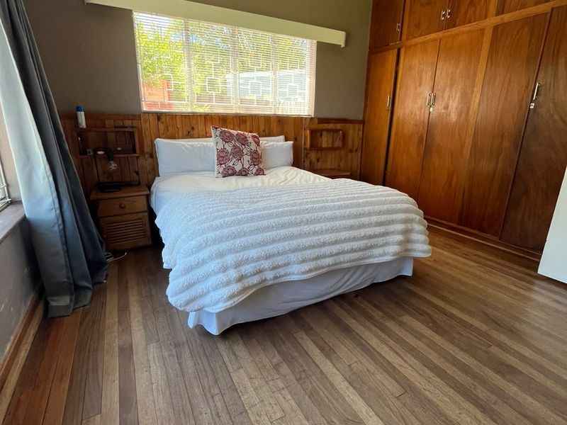 A bedroom featuring extensive built-in wooden cabinetry, warm-toned wooden flooring, and a matching wooden headboard with integrated shelving.