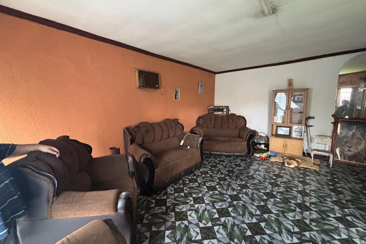 A living room featuring patterned tiled flooring and an integrated wall-mounted air conditioning unit, requiring cosmetic updates to improve the overall aesthetic.