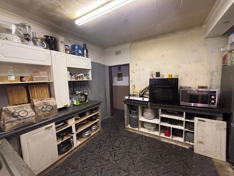 A dated kitchen featuring built-in cabinetry, stone countertops, and a built-in oven, requiring significant cosmetic renovation and wall repairs.