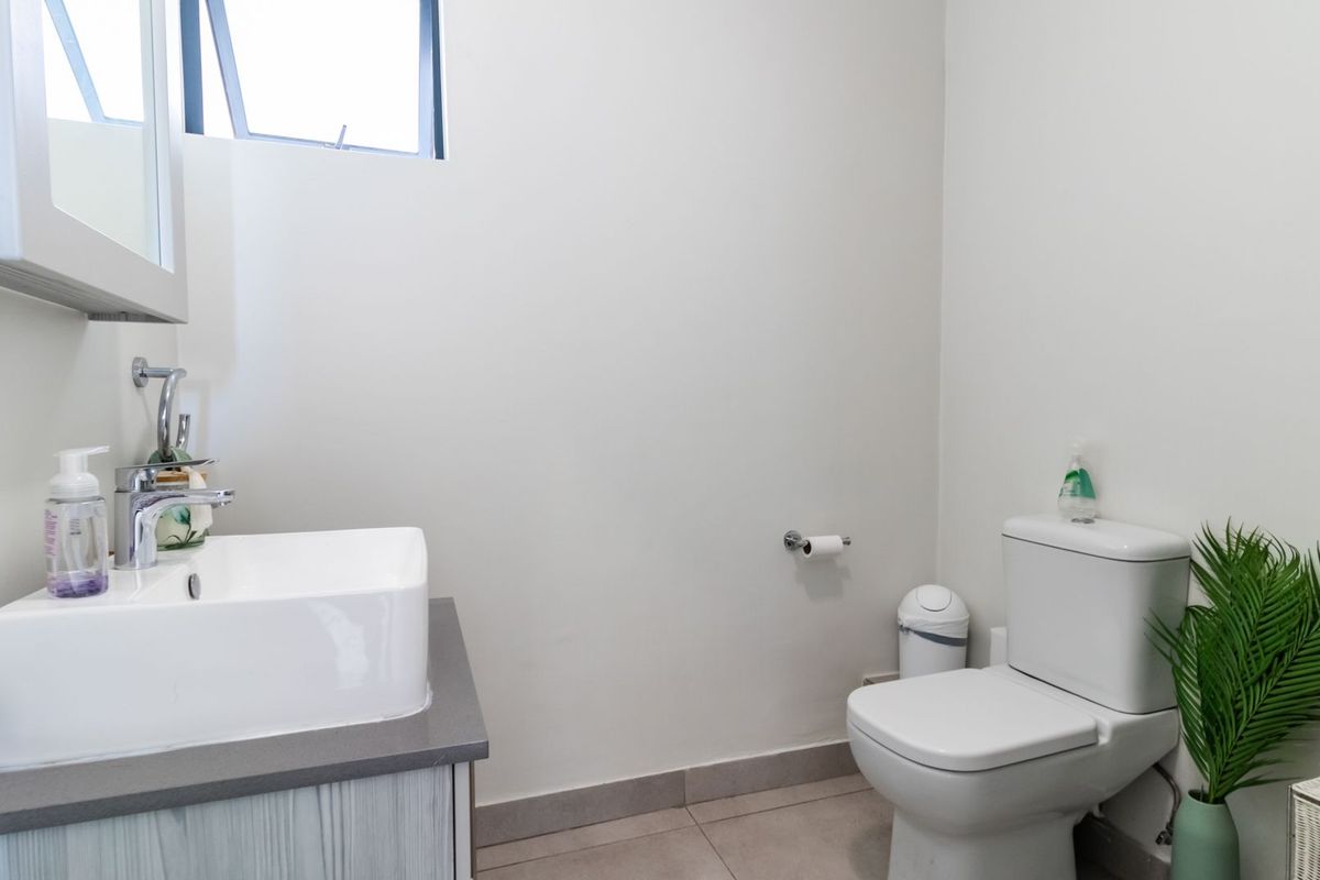 A clean and functional bathroom featuring a modern vessel sink on a vanity cabinet, a standard toilet, and tiled flooring.