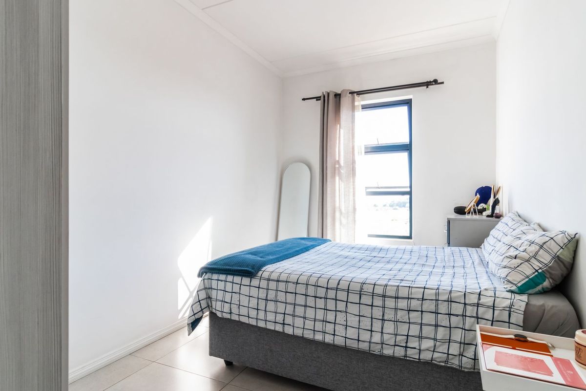 A bright and well-maintained bedroom featuring tiled flooring and a large window that allows for ample natural light.