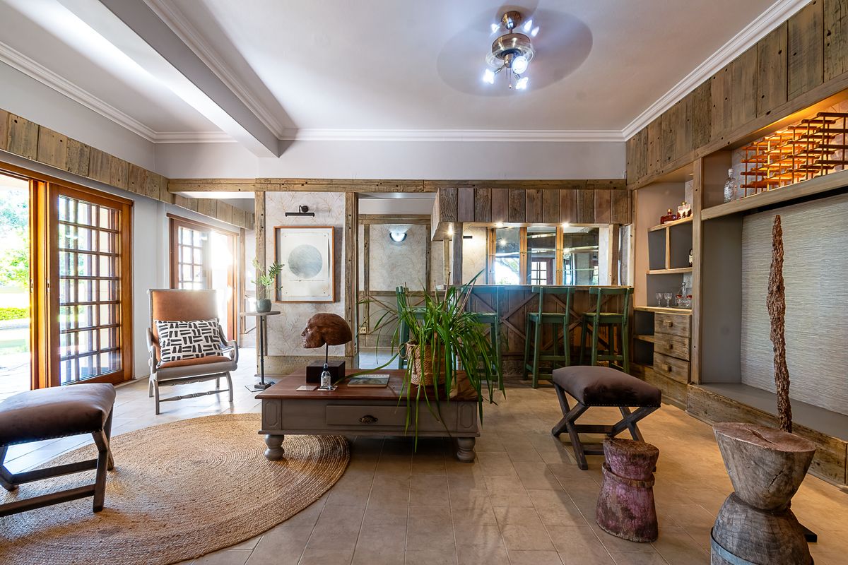 Spacious living area featuring a built-in timber bar, rustic wood wall paneling, tiled floors, and large sliding glass doors leading to the outdoors.