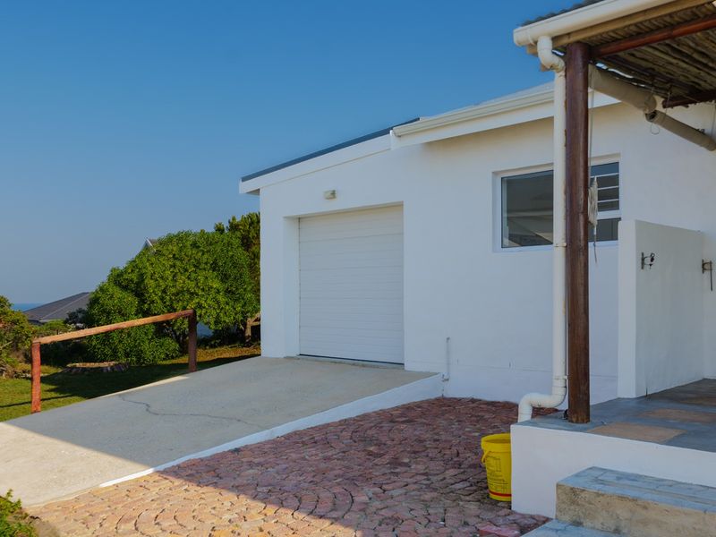 Exterior view of the property featuring a single garage, concrete driveway with minor cracking, and a paved patio area with timber support.