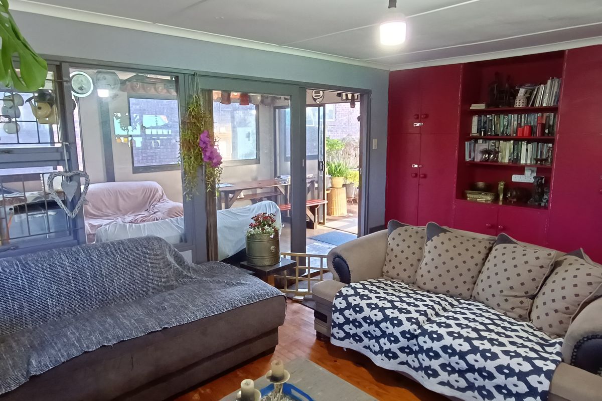 A living room featuring timber flooring, built-in cabinetry, and large sliding glass doors providing access to an enclosed patio area.