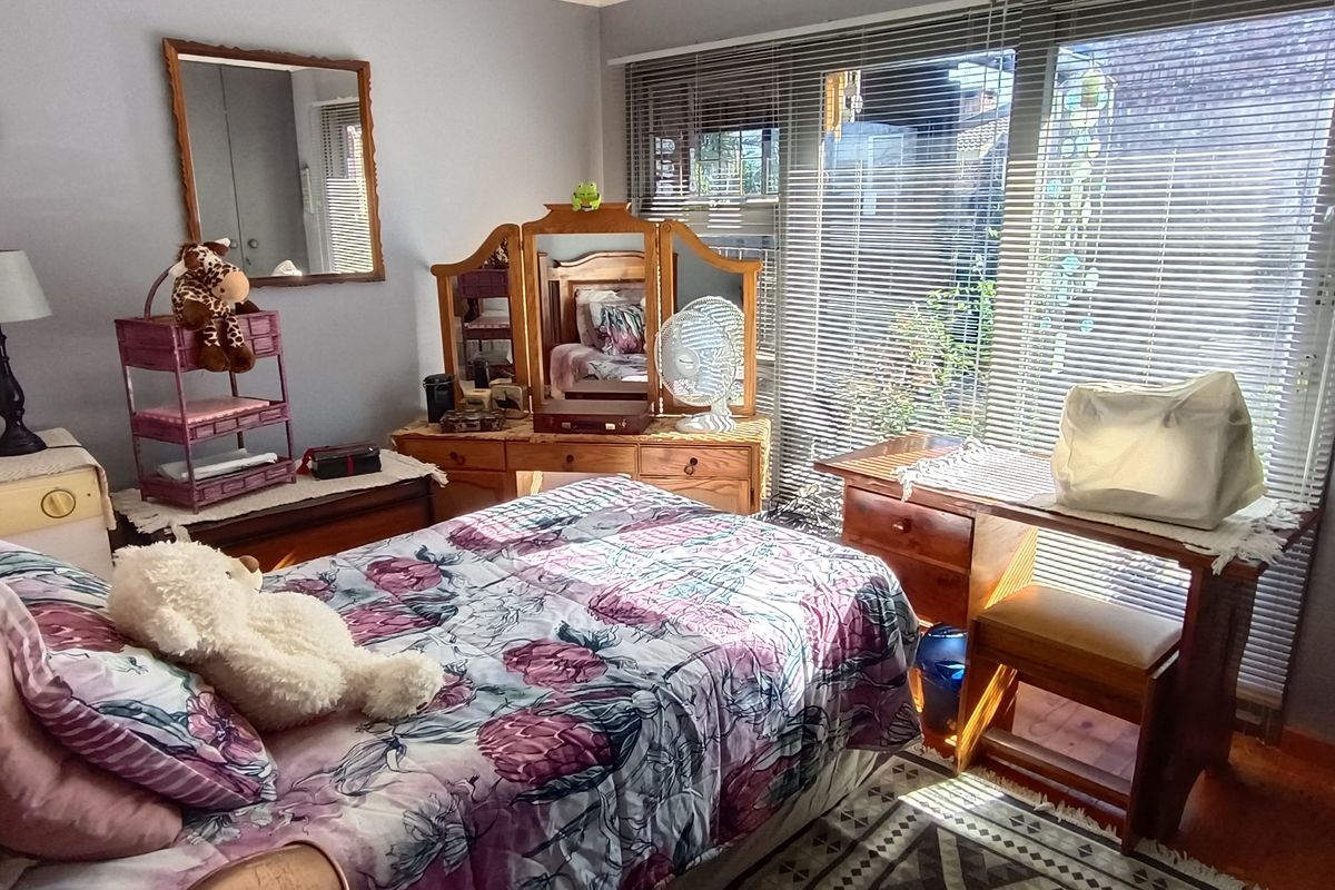 A bedroom featuring hardwood flooring and a large sliding glass door with venetian blinds, providing natural light and access to the exterior.