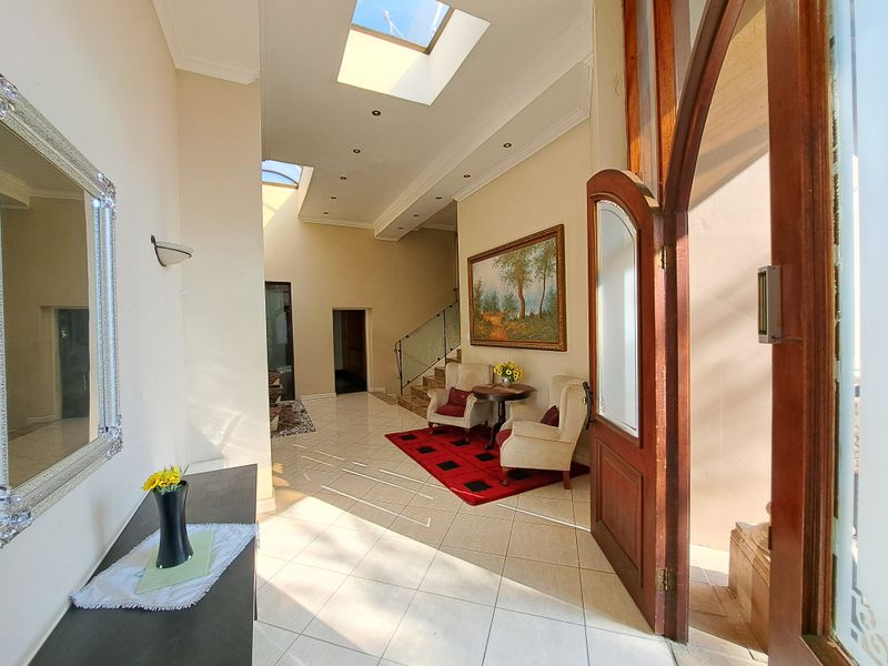 Spacious entrance hall featuring tiled flooring, a grand arch-top timber door, and multiple skylights that provide abundant natural light to the interior space.