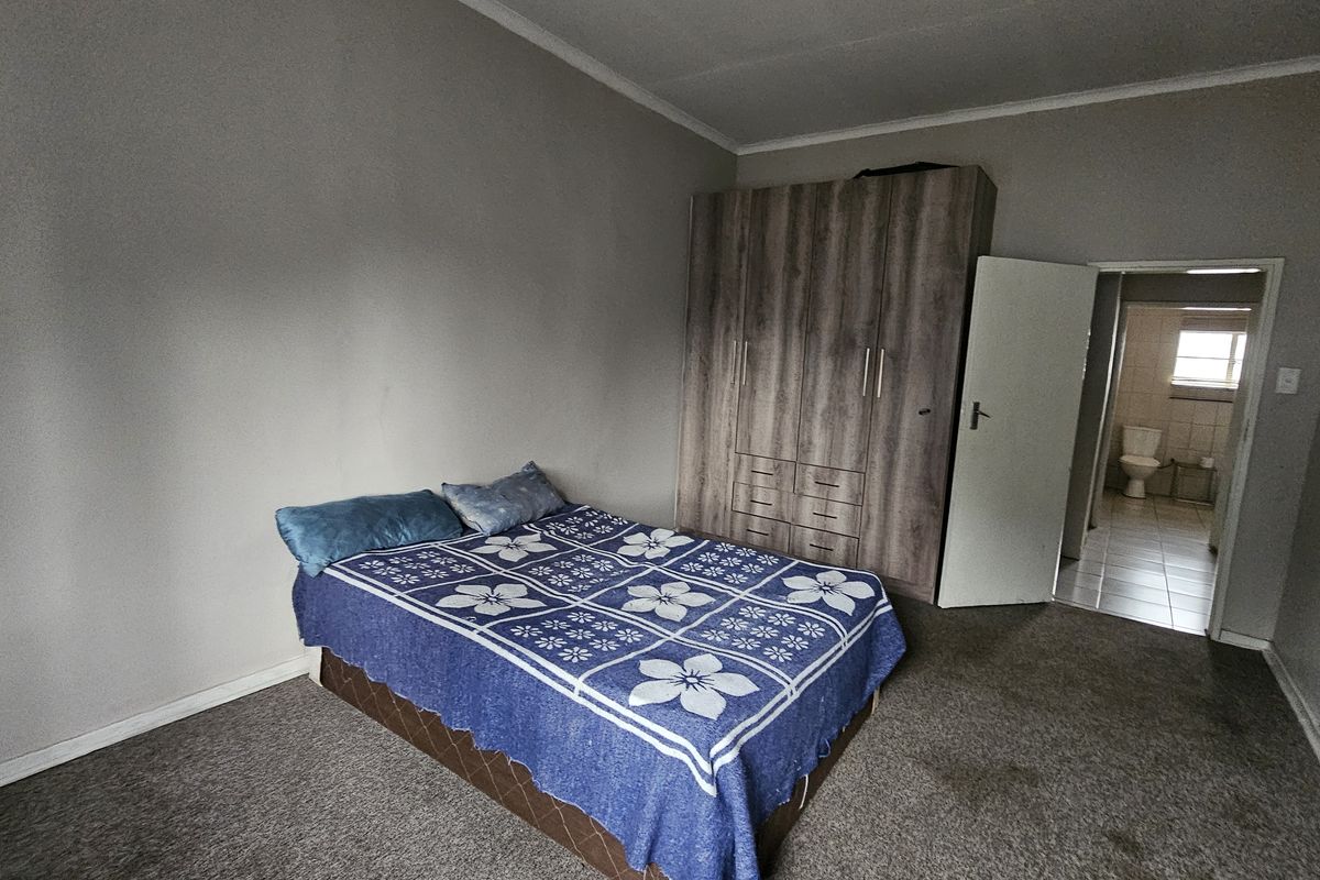 A bedroom featuring a built-in wardrobe, carpeted flooring, and direct access to an en-suite bathroom.