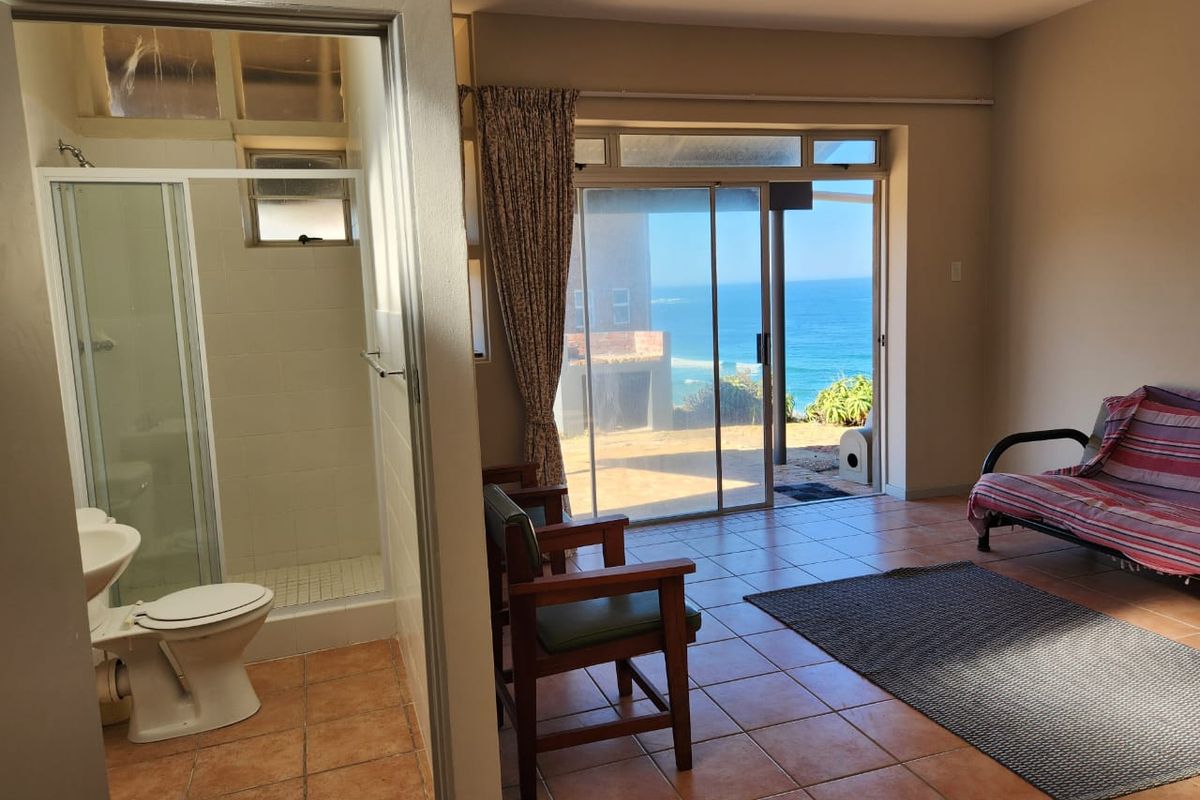 Bedroom with an en-suite bathroom, tiled flooring, and sliding glass doors opening to a patio with ocean views.