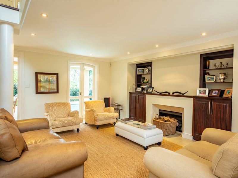 A well-maintained living room featuring built-in cabinetry, a fireplace, recessed lighting, and french doors leading to an outdoor area.
