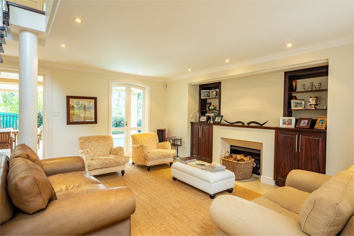 A well-maintained living room featuring built-in cabinetry, a fireplace, recessed lighting, and french doors leading to an outdoor area.