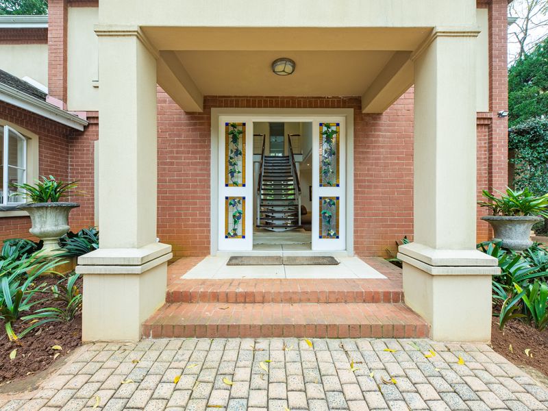 A welcoming front entrance featuring a brick facade, covered porch with concrete columns, and a decorative stained glass front door.