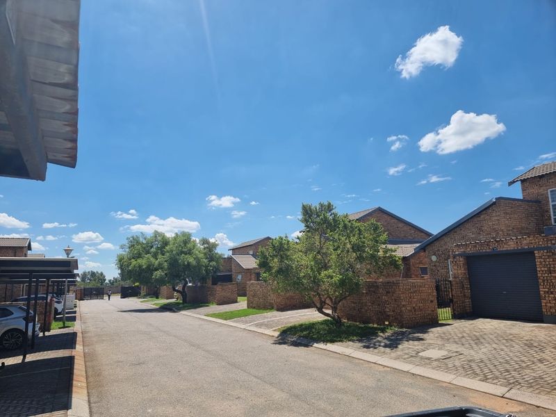 A view of the residential street within the apartment complex, featuring brick-faced units, paved driveways, and covered parking areas.