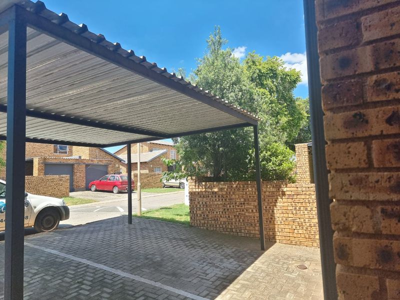 A covered carport area with paved flooring and brick boundary walling, providing dedicated off-street parking.