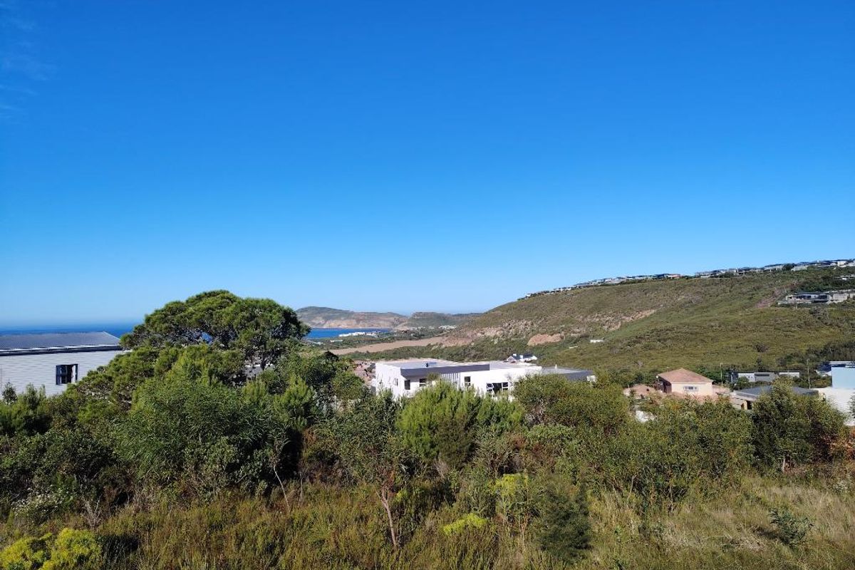 A scenic elevated view overlooking the surrounding coastal landscape, native vegetation, and nearby residential developments under a clear blue sky.