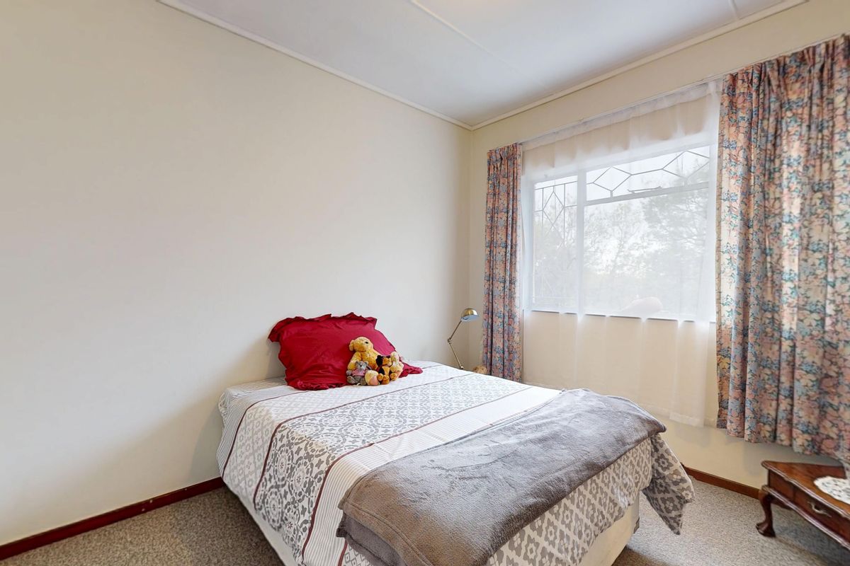 A functional bedroom featuring a built-in wardrobe and a window with decorative leaded glass detailing.