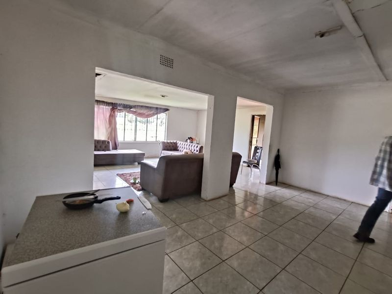 Open plan living area featuring tiled flooring and large openings connecting to adjacent rooms, providing a spacious layout with potential for modernization.