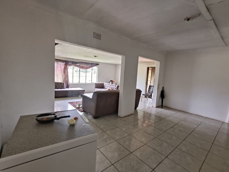 Open plan living area with tiled flooring and large openings connecting to adjacent rooms, providing a spacious layout.